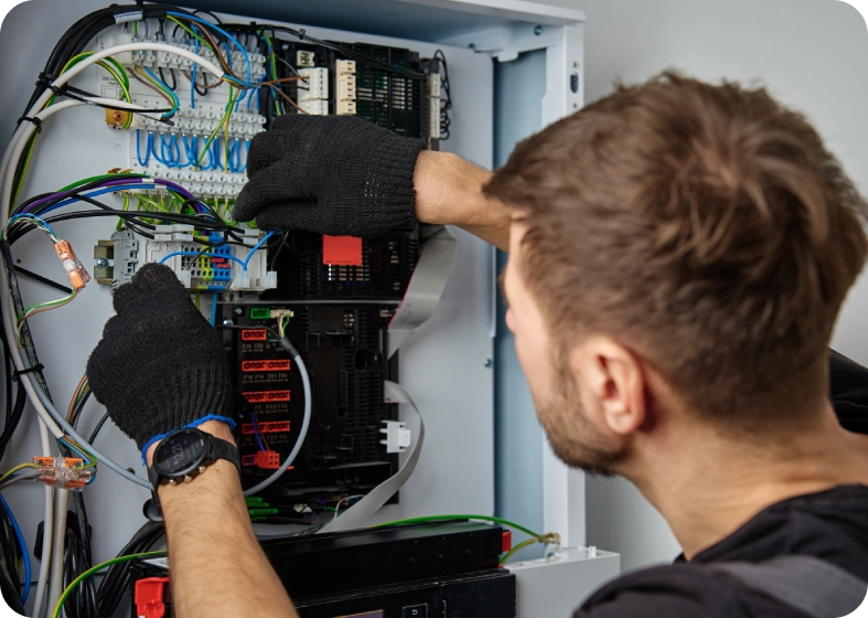 Technician inspecting complex electrical wiring inside a panel.