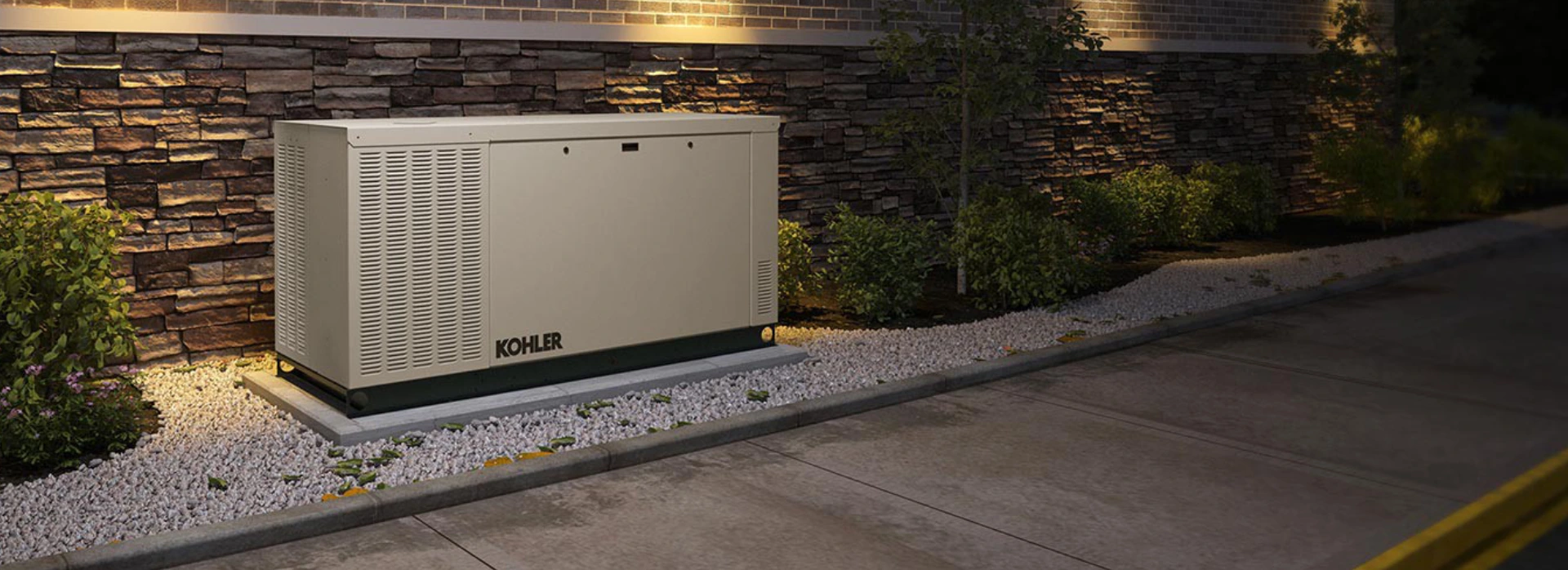 A Kohler generator outside on gravel near a concrete driveway.